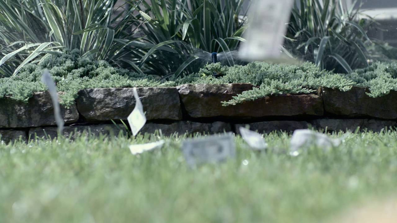 Published commercial thumbnail showing a sprinkler and money blowing across a lawn